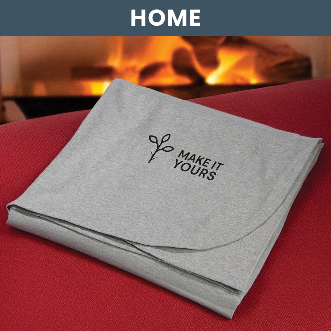 Lifestyle image of a blanket resting on couch, beside a cozy fireplace