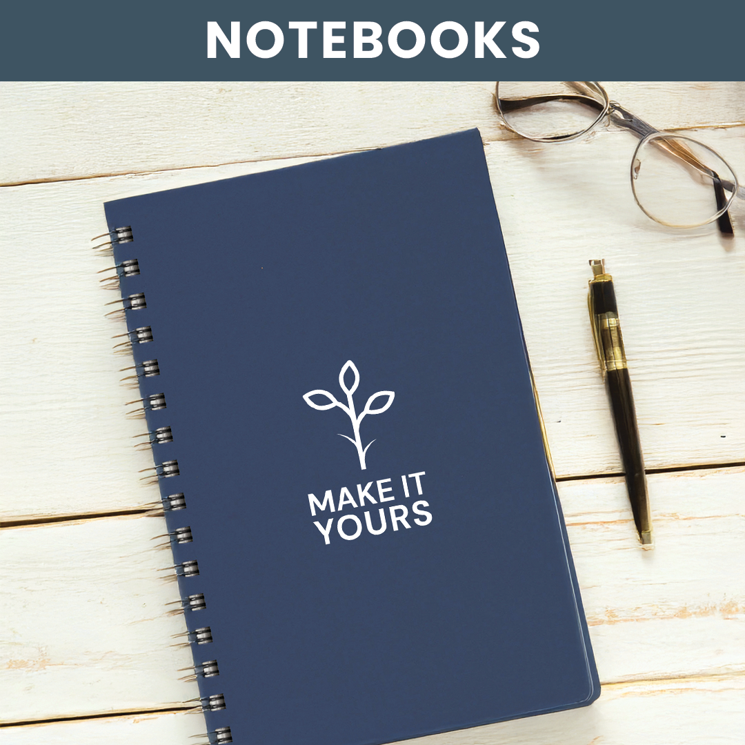 Lifestyle image of a notebook laying on wooden surface, pair of glasses and a pen beside notebook